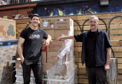 Two people standing in front of boxes of food at a food bank